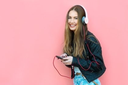 دانلود زیبا زن خوشحال در هدفون گوش دادن موسیقی در نزدیکی دیوار