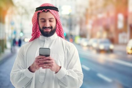 دانلود بازرگان عرب با تلفن خود در یک خیابان شلوغ در پس زمینه کار می کند