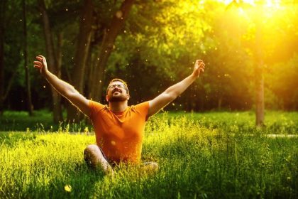دانلود یک مرد شاد در چمن سبز با چشمان کج و معوج و در روز تابستان آفتابی در پسزمینه پارک به سوی اسباب بازی ها می آید. کنک