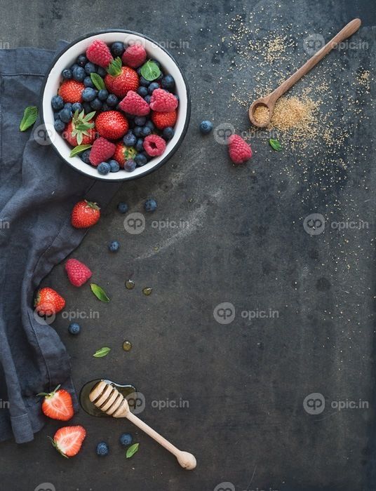 دانلود قاب برفی با فضای کپی در سمت راست. توت فرنگی، تمشک، زغال اخته و برگ نعنا، عسل، شکر نیشکر، پس زمینه گرانج تاریک،