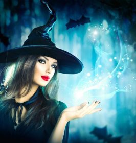دانلود جادوگر هالووین با سحر و جادو در جنگل تاریک. زن جوان زیبا در کلاه و کلاه جادوگر که دارای نور جادویی در دست او است. هنر هالووین d