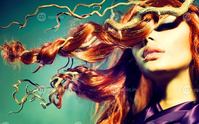 دانلود موی قرمز. پرتره زنانه مدل مد با موهای قرمز بلند مجعد در شاخه های چوبی. فصل پاييز. اکستنشن مو