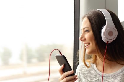 دانلود مسافر نوجوان مبارک در حال گوش دادن به موسیقی است که در قطار مسافرت می کند و از پنجره نگاه می کند