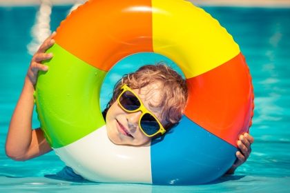 دانلود کودک خوشحال در استخر شنا بازی می کند. مفهوم تعطیلات تابستانی