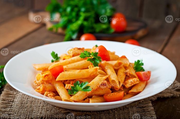 دانلود ماکارونی پن پنیر در سس گوجه فرنگی با مرغ ، گوجه فرنگی تزئین شده با جعفری در یک پس زمینه چوبی_001