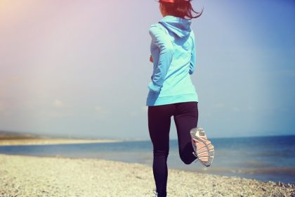 دانلود ورزشکار دونده ای که در ساحل سنگی در حال دویدن است. مفهوم سلامتی تمرین آهسته دویدن تناسب اندام زن.