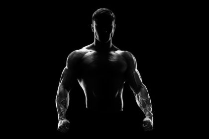 دانلود شبح یک بدنساز قوی. مرد تناسب اندام جوان با دستان قوی و مشت های محکم. عکس سیاه و سفید. dramatic light