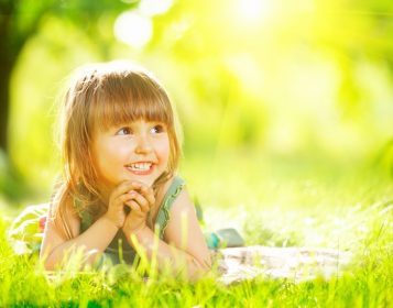 دانلود پرتره یك دختر كوچك لبخند بر روی چمن سبز. کودک سه ساله ناز از طبیعت خارج از منزل لذت می برد