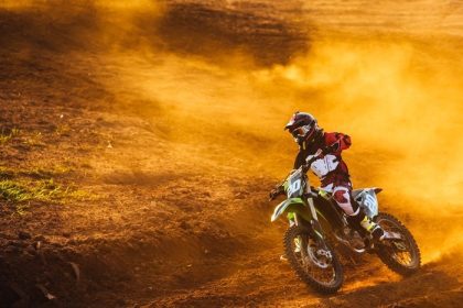 دانلود خلبان Motocross به نوبه خود در هنگام غروب آفتاب با دود طلایی در مسیر خاکی