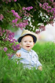 دانلود کودک نوپا در چمنزارها در یک علفزار نشسته است. نوزادی در پس زمینه طبیعت. کودک در گل. Kid