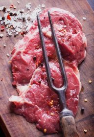 دانلود گوشت تازه خام Ribeye استیک ، با چاشنی و چنگال گوشت در تخته چوبی پرنعمت
