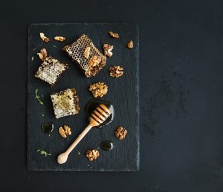 دانلود لانه زنبوری ، گردو و شیرین کننده عسلی روی سینی تخته سنگ مشبک بر روی زمینه تاریک grunge ، نمای بالا ، فضای کپی