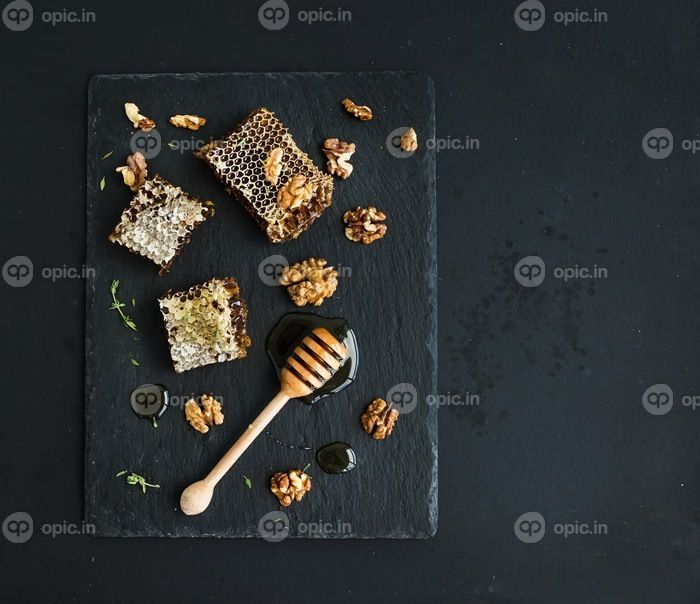 دانلود لانه زنبوری ، گردو و شیرین کننده عسلی روی سینی تخته سنگ مشبک بر روی زمینه تاریک grunge ، نمای بالا ، فضای کپی
