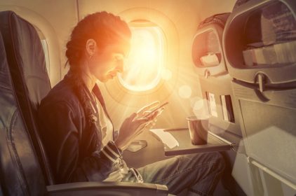 دانلود زنی که در هواپیما نشسته و به دنبال تلفن همراه است