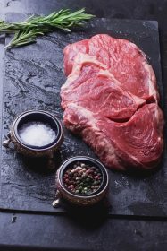 دانلود استیک گوشت گاو Sirloin گوشت گاو ایرلندی خام در تخته سنگ سنگی آماده برای بو داده با رزماری ، فلفل قرمز و فلفل دلمه ای و نمک_002