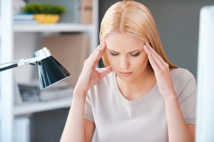 دانلود احساس استرس. زن جوانی ناامید که هنگام نشستن در محل کار خود در دفتر ، سرش را لمس کرده و چشمان خود را بسته نگه می دارد