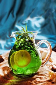 دانلود کوکتل لیموناد الکلی را با کوزه سبز ترخون لیمو در ماسه در نوار ساحل بنوشید