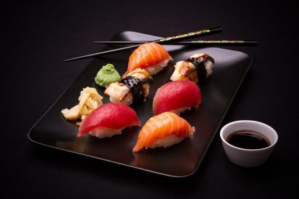 دانلود سوشی مارماهی ، ماهی قزل آلا و ماهی تن با chopsticks ، پس زمینه تیره