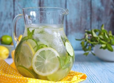 دانلود آب میوه را با گل لیمو ، لیمو ، خیار و نعنا در پارچ شیشه ای قرار دهید