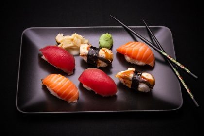 دانلود سوشی مارماهی ، ماهی قزل آلا و ماهی تن با خردسالان ، پس زمینه تیره ، نمای بالا