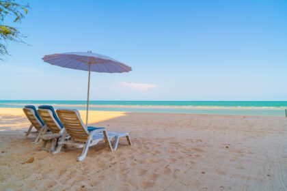 دانلود عکس صندلی ساحلی روی ماسه با پس زمینه دریای اقیانوس