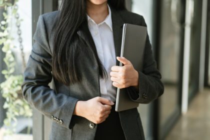 دانلود عکس زن تجاری که لپ تاپ را در دفتر اداری به دست دارد