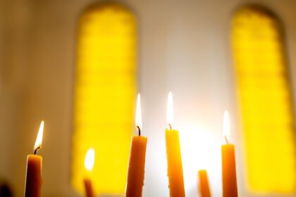 دانلود عکس شمع سوزان در کلیسا در پس زمینه تار