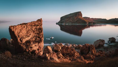 دانلود عکس سنگ های بزرگ دریاچه ارومیه با کوه ها و آسمان آبی صاف در ایران