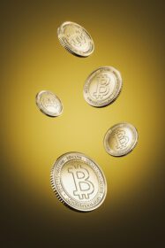 دانلود عکس سکه های طلایی بیت کوین شناور در پس زمینه زرد برای ارز دیجیتال