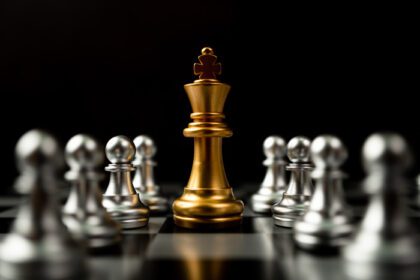 دانلود عکس شاه شطرنج طلایی ایستاده در اطراف شطرنج دیگر