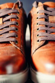 دانلود عکس یک جفت کفش مردانه قهوه ای بند دار به عنوان پس زمینه از نزدیک
