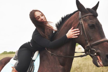 دانلود عکس دختر ناز جوانی که اسبش را در حالی که سوار بر او نشسته در آغوش گرفته است