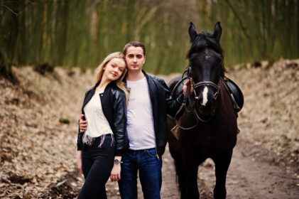 دانلود عکس زوج جوان شیک و عاشق در نزدیکی اسب در جنگل پاییزی