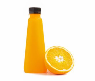 دانلود عکس یک بطری پر از آب پرتقال و نیم برش مرکبات تکیه داده شده