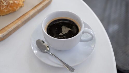 دانلود عکس یک فنجان قهوه روی میز سفید با غذای زمان استراحت کار