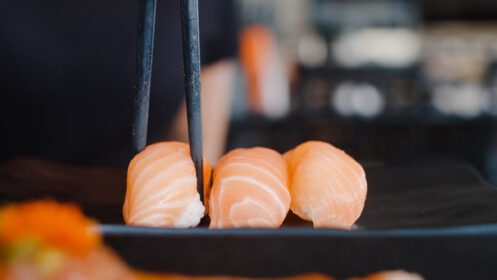 دانلود عکس زن آسیایی در حال خوردن سوشی در رستوران ژاپنی جوان