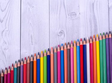 دانلود عکس مداد رنگی چوبی چیده شده به شکل نردبان بر روی پس زمینه خاکستری و سفید مفهوم آموزش