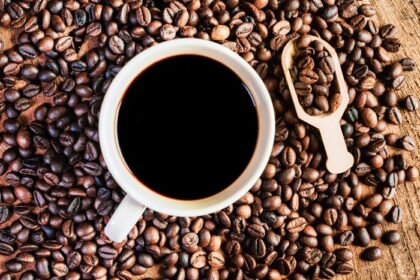 دانلود عکس قهوه سیاه در فنجان دانه های قهوه تیره روی چوبی قدیمی