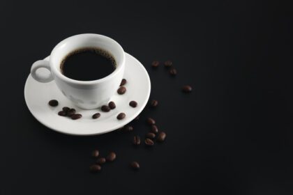 دانلود عکس قهوه سیاه در فنجان قهوه سفید و نعلبکی با دانه ها