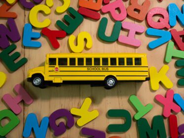 دانلود عکس الفبای چوبی چند رنگ و اتوبوس مدرسه روی میز برای