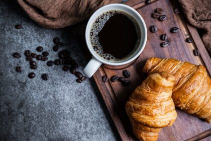 دانلود عکس صبحانه با کروسانت تازه و فنجان قهوه سیاه در