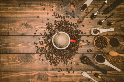 دانلود عکس دانه های قهوه قهوه ای و یک فنجان قهوه داغ روی الف