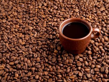 دانلود عکس فنجان قهوه ای اسپرسو با پس زمینه قهوه پراکنده