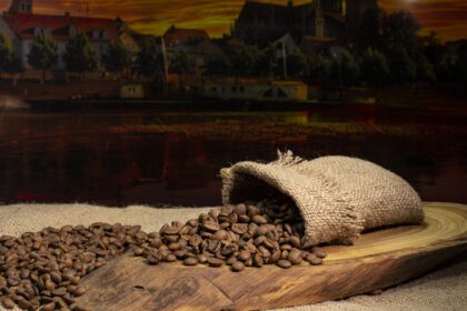 دانلود عکس دانه های قهوه در گونی و منظره شهری در پس زمینه