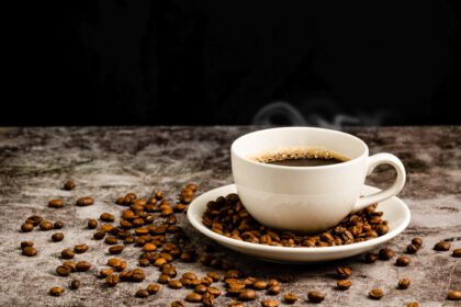 دانلود عکس از نزدیک قهوه داغ در فنجان سفید روی سیمان قرار گرفته است