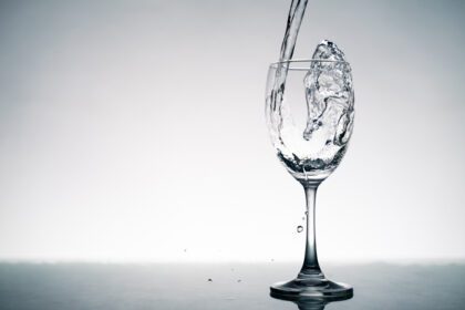 دانلود عکس نزدیک از پاشیدن آب کریستالی که در لیوان شراب روی میز ریخته می شود