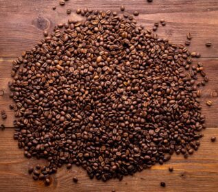 دانلود عکس از نزدیک دانه های قهوه بو داده در پس زمینه چوبی قهوه ای
