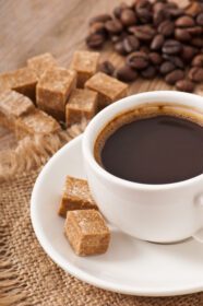 دانلود عکس نمای نزدیک از یک فنجان قهوه شکر قهوه ای و دانه های قهوه