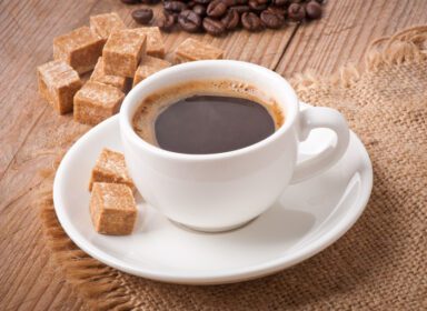 دانلود عکس نمای نزدیک از یک فنجان قهوه شکر قهوه ای و دانه های قهوه