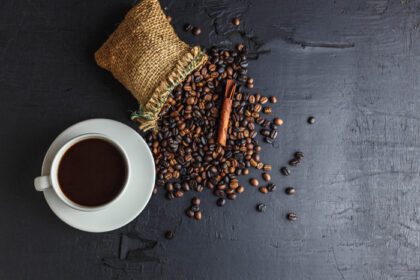 دانلود عکس دانه های قهوه در کیسه گونی قهوه ای با فنجان قهوه روی مشکی